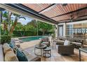 Covered outdoor living space with a built-in kitchen, comfortable seating, and pool view at 141 S Phelps Ave, Winter Park, FL 32789