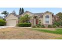 Charming one-story home with a light-colored exterior, brick details, and lush green landscaping at 144 Henue Ct, Davenport, FL 33896