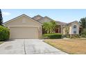 Well-maintained single-story home featuring a tan exterior, palm trees, and a two-car garage at 144 Henue Ct, Davenport, FL 33896