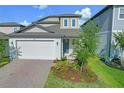 Beautifully landscaped two-story home with a brick driveway, attached two-car garage, and welcoming front entrance at 2304 Mystic Maze Ln, Clermont, FL 34715