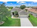 An elevated view of a well-kept home showing the 2-car garage, driveway, and tree-shaded lawn at 27401 Pine Straw Rd, Leesburg, FL 34748