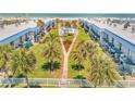 Aerial view of condominiums with a community pool, palm trees, and manicured lawns that lead to the ocean at 2750 Ocean Shore Blvd # 350, Ormond Beach, FL 32176