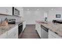 Modern kitchen featuring granite countertops, white cabinets, stainless steel appliances, and hardwood floors at 3017 Ambersweet Pl, Clermont, FL 34711