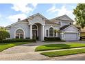 Two-story home with a paved driveway, arched windows, and lush landscaping at 3891 Brantley Place Cir, Apopka, FL 32703
