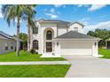 Inviting two-story home featuring an arched entryway, attached two-car garage, and a well-manicured lawn with a palm tree at 4751 Aguila Pl, Orlando, FL 32826