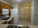 Functional kitchen with white appliances, oak cabinets, and tile flooring at 672 Post Oak Cir # 106, Altamonte Springs, FL 32701