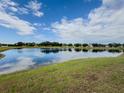 Scenic view of the community pond with calm, reflective water under a bright blue sky with fluffy clouds at 11091 Bagley Aly, Windermere, FL 34786