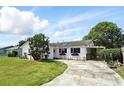Charming single-story home with white exterior, dark shutters, and a spacious front yard at 114 Floral Dr, Kissimmee, FL 34743