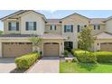 Inviting townhome with tiled roof, two-car garage, and manicured greenery enhancing its curb appeal at 13993 Tarvin St, Orlando, FL 32832