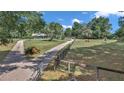 Scenic view of a home with a long driveway and fenced yard, set amidst mature trees at 2299 Nw 135Th Ln, Citra, FL 32113