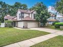 Two-story home featuring a well-maintained lawn, brick accents, an attached two-car garage and a sidewalk at 2706 Donaldson Dr, Orlando, FL 32812