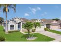 Inviting one-story home with tropical landscaping, a well-maintained lawn, and an attached garage at 2975 White Cedar Cir, Kissimmee, FL 34741