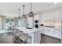 Bright, all-white kitchen featuring pendant lighting, modern appliances, and an island with barstool seating at 3361 Orange Rose Loop, Apopka, FL 32712