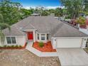 Aerial view of a charming single-story home with a red front door, lush landscaping, and an attached two-car garage at 404 Wilshire Dr, Casselberry, FL 32707