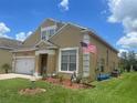 Charming two-story home with a well-maintained lawn, brick paved driveway, and an attached two-car garage at 447 Cadiz Loop, Davenport, FL 33837