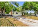 Cozy yellow cottage with lush green trees, a long driveway, and a well-maintained lawn at 5750 Delta St, Orlando, FL 32807