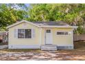 Adorable yellow cottage-style home with a white front door and well-maintained yard at 5750 Delta St, Orlando, FL 32807
