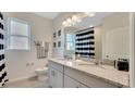 Stylish bathroom featuring double sinks with granite countertops, modern fixtures, and a coordinated black-and-white theme at 7213 Nottingham Reel Ct, St Cloud, FL 34773