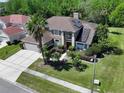 A captivating aerial shot showcasing a two-story home with solar panels nestled amidst mature trees and a manicured lawn at 12618 Greco Dr, Orlando, FL 32824