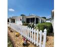 Home exterior featuring a charming screened-in lanai area, and a neatly maintained yard with a white picket fence at 16922 Se 81St Charlesfort Ave, The Villages, FL 32162
