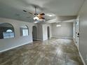 Open-concept living room featuring neutral paint, tile floors, a ceiling fan, and arched doorways at 1912 Conch Ln, Kissimmee, FL 34759