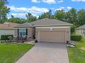 Inviting single-Gathering home with a well-manicured lawn, brick driveway, and attached two-car garage at 2217 Caledonian St, Clermont, FL 34711