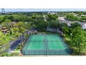Aerial view of two green tennis courts surrounded by a black fence, lush trees and a parking area at 315 Lakepointe Dr # 101, Altamonte Springs, FL 32701