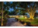 Inviting home exterior at twilight with landscape lighting highlighting mature trees and manicured grounds at 502 Oak Ln, Maitland, FL 32751