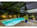 Nighttime view of a sparkling in-ground pool with an enclosed screen and outdoor seating area at 502 Oak Ln, Maitland, FL 32751