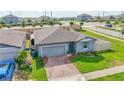 Aerial view of a well-kept home with a brick driveway, lush lawn, and fenced backyard at 719 Tortugas St, Haines City, FL 33844