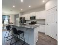 Well-lit kitchen with white cabinets, stainless steel appliances, and an island with bar seating, open to the dining area at 1167 Celery Oaks Ln, Sanford, FL 32771