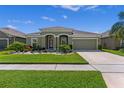 Charming single-story home featuring lush green lawn, colorful flower beds, and a driveway leading to a two-car garage at 12289 Prairie Plantation Way, Orlando, FL 32824