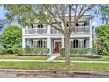 Charming two-story home with a red door, white columns, and a welcoming front porch at 13505 Phoenix Dr, Orlando, FL 32828