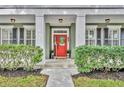 Inviting front porch with a bright red door, sidelights, and manicured landscaping at 13505 Phoenix Dr, Orlando, FL 32828