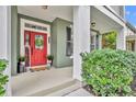 Inviting front porch with a bright red door, sidelights, and manicured landscaping at 13505 Phoenix Dr, Orlando, FL 32828