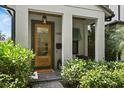 Elegant front entry with a wood door, stylish light fixture, and verdant landscaping for added curb appeal at 1429 Indiana Ave, Winter Park, FL 32789