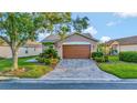 Charming home featuring a two-car garage with a brick-paved driveway, accent lighting, and well-manicured landscaping at 149 Acadia Dr, Kissimmee, FL 34759