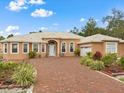 Captivating single-story home with a brick driveway, manicured landscaping, arched entryway, and durable metal roof at 2002 Adair St, Ocoee, FL 34761