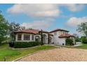 Beautiful stucco home with red tile roof, lush landscaping, and curved gravel driveway at 3437 Coronet Ave, Orlando, FL 32833