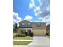 Inviting two-story home with a spacious driveway, beautiful lawn and vibrant blue window shutters at 651 Taft Dr, Davenport, FL 33837