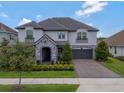 Beautiful two-story home with a stone entrance, lush landscaping, and a two-car garage at 10742 Belle Maisons Dr, Orlando, FL 32832