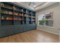 Stylish library room showcasing custom blue built-in shelving and wood floors at 10819 Savona Way, Orlando, FL 32827