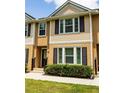Attractive two-story townhome featuring tan siding, black shutters, and green shrubs at 1255 Marley Ln, Winter Springs, FL 32708