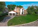 Beautiful home with a stone turret, red tile roof, two-car garage, and verdant lawn at 1401 Green Cove Rd, Winter Park, FL 32789
