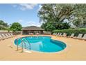 Community pool with lounge chairs, surrounded by mature trees and a screened cabana at 1401 Yellow Finch Dr, Davenport, FL 33837