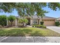 Charming single-story home with lush green lawn, mature trees, and attached two-car garage at 14848 Bonnybridge Dr, Orlando, FL 32826