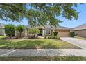 Charming single-story home with lush green lawn, mature trees, and attached two-car garage at 14848 Bonnybridge Dr, Orlando, FL 32826