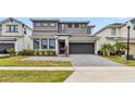 Modern home featuring a two-car garage, gray driveway, and well-maintained landscaping in the front yard at 2574 Shanti Dr, Kissimmee, FL 34746