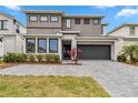 Modern home with two-car garage, gray driveway, landscaping, and a two-tone gray and white facade at 2574 Shanti Dr, Kissimmee, FL 34746