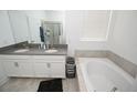 Bright bathroom with double sinks, a soaking tub, and elegant finishes at 3027 Addison Blvd, St Cloud, FL 34771